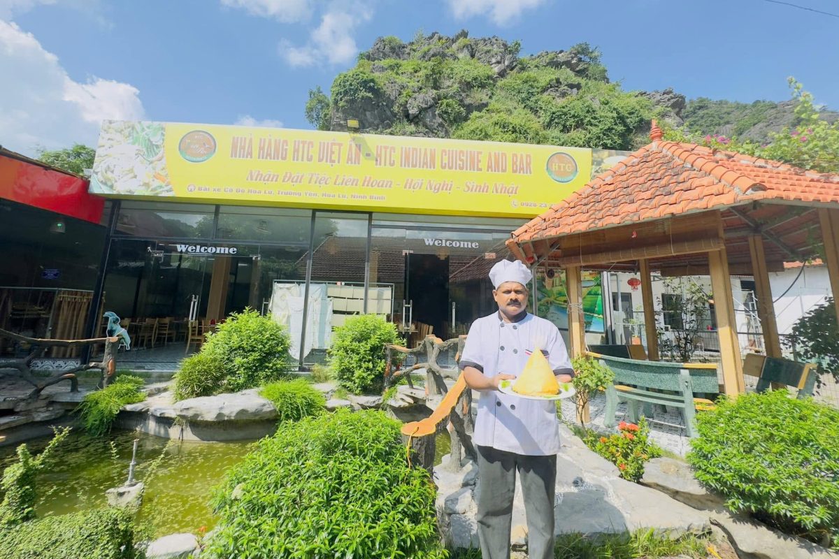 Indian chef holding a plate outside HTC Viet An halal restaurant at the Hoa Lu ancient capital car park, Ninh Binh