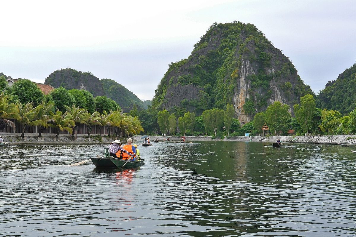 Boats on the river through rice fields and karst mountains at Tam Coc, Ninh Binh